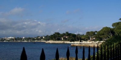 Vista de Juan les Pins desde la carretera con árboles, mar y edificios al fondo