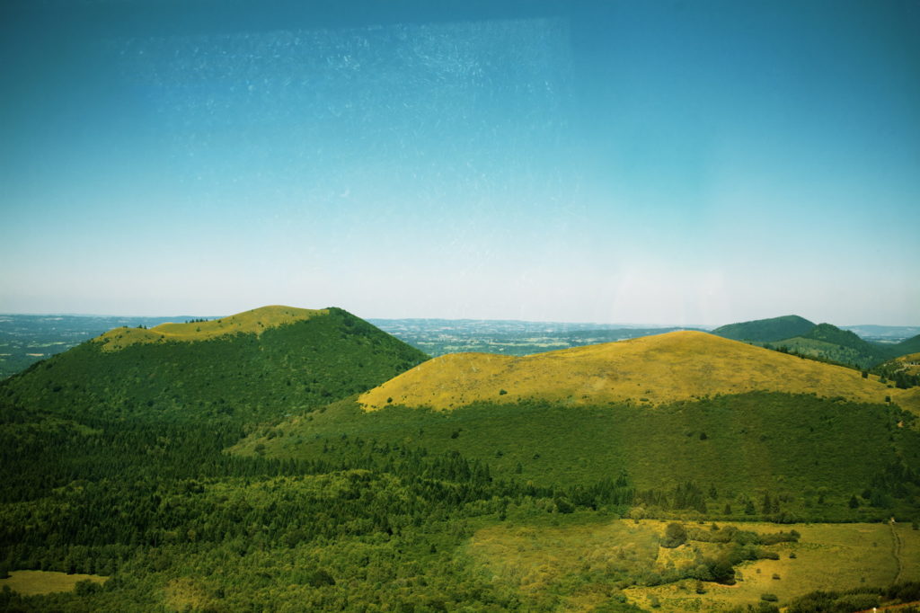 Vista aérea de la región volcánica de Auvernia con amplias colinas verdes y valles profundos 