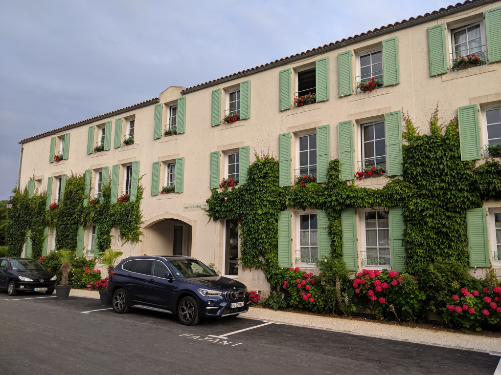 Un hotel de 3 plantas con paredes blancas y persianas verdes en San Martín