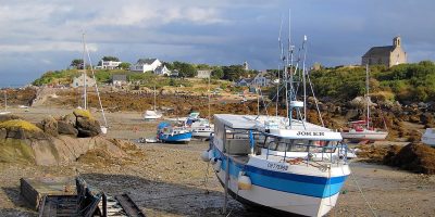 Un barco de pesca en una playa de arena con otros detrás en un puerto en las Islas Chausey, Francia