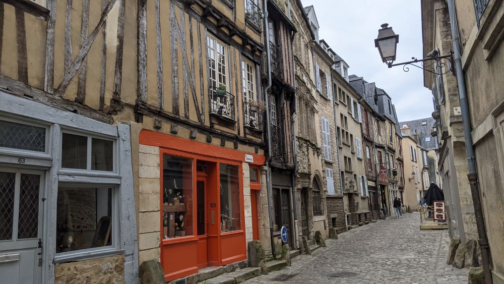 Una estrecha calle adoquinada en Le Mans con casas de entramado de madera y adoquines