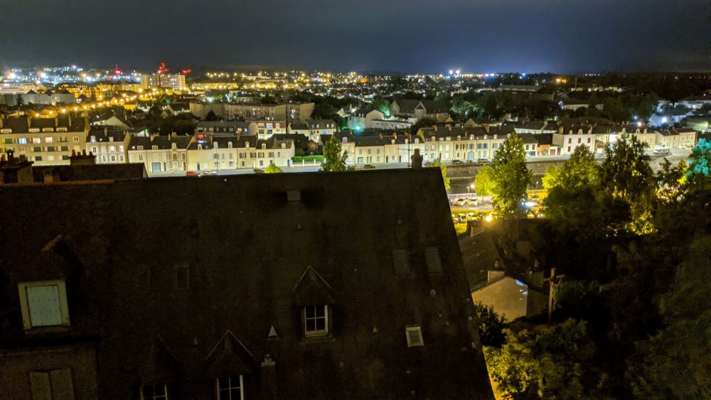 Una vista desde lo alto de Le Mans con vistas a un techo empinado y el exterior de las casas cargadas a lo largo del río