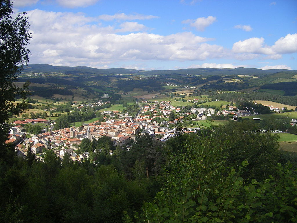 Vista de Le Malzieur-Vielle desde la cima de la colina del pueblo en una colina con pendiente y las colinas de Margueride al fondo