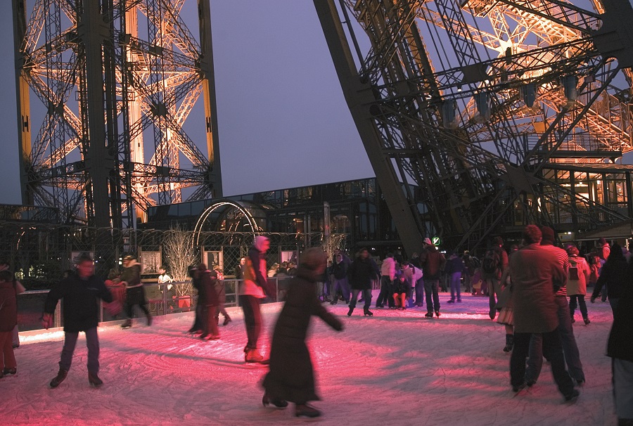 Patinaje nocturno bajo la Torre Eiffel con figuras sobre patines e iluminado con un resplandor rojo