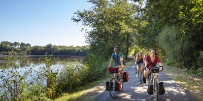 Dos adultos y otra persona detrás de ciclismo cerca del Valle del Loira en Sologne, con alforjas llenas en bicicletas