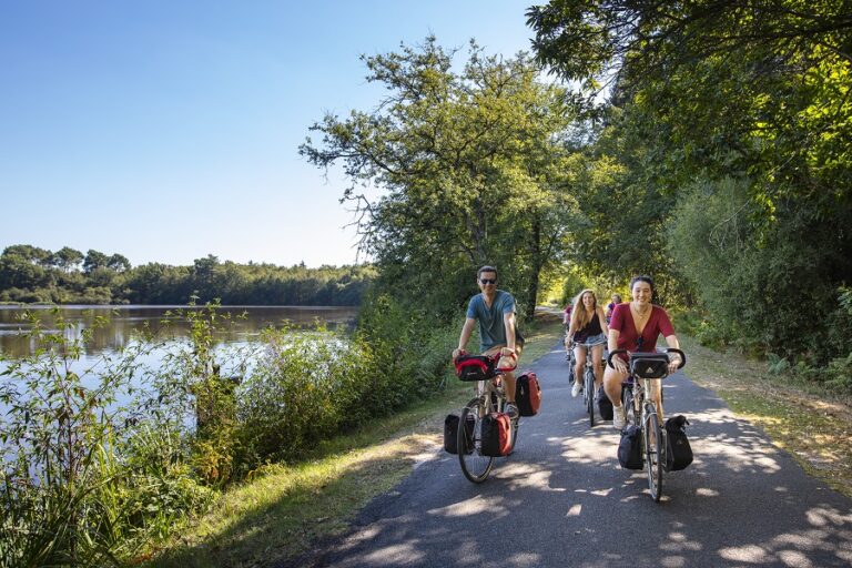 Dos adultos y otra persona detrás de ciclismo cerca del Valle del Loira en Sologne, con alforjas llenas en bicicletas