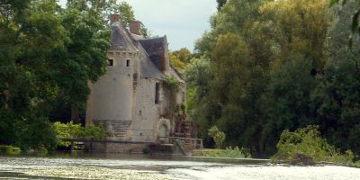 El Moulin de Merve Loir Valley con un molino de piedra y una torre al fondo y un río en primer plano