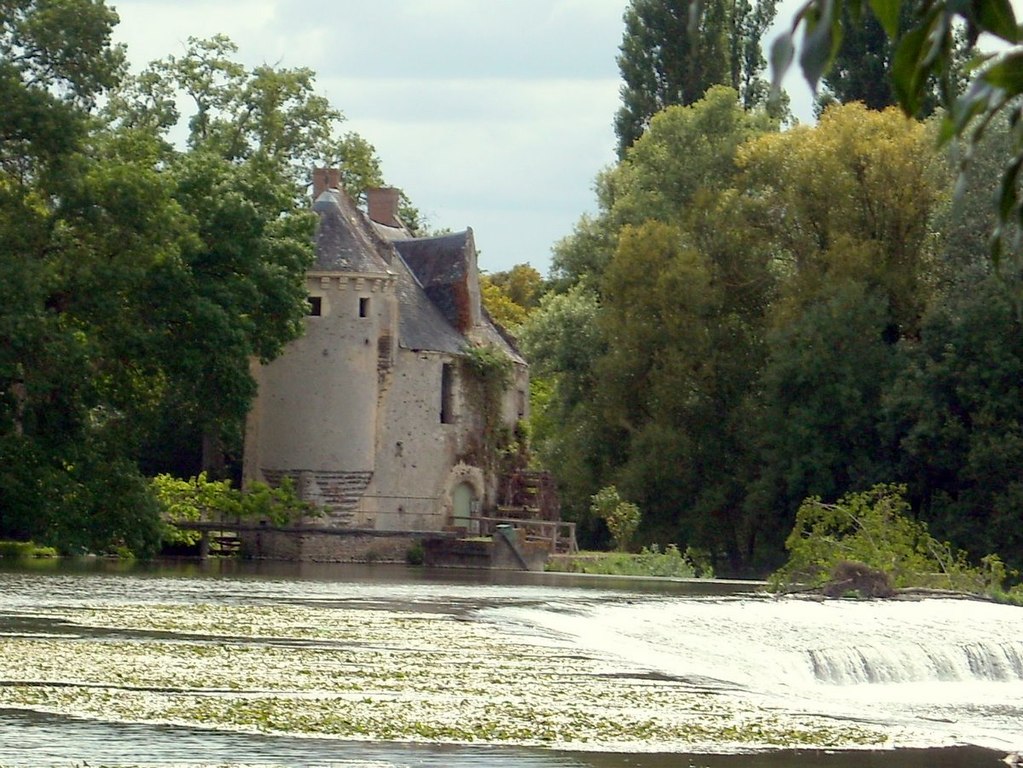 El Moulin de Merve Loir Valley con un molino de piedra y una torre al fondo y un río en primer plano