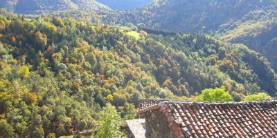 Vista sobre el valle del río y las altas colinas en la distancia y la casa de techo rojo debajo