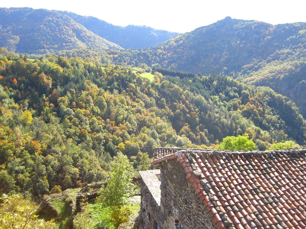 Vista sobre el valle del río y las altas colinas en la distancia y la casa de techo rojo debajo