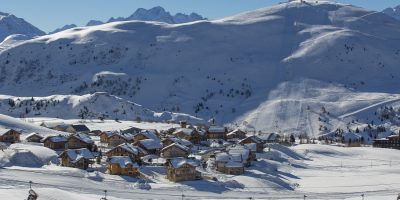 Vista de la estación de esquí de Alpe d'Huez en invierno con teleféricos frente al pueblo y picos nevados detrás