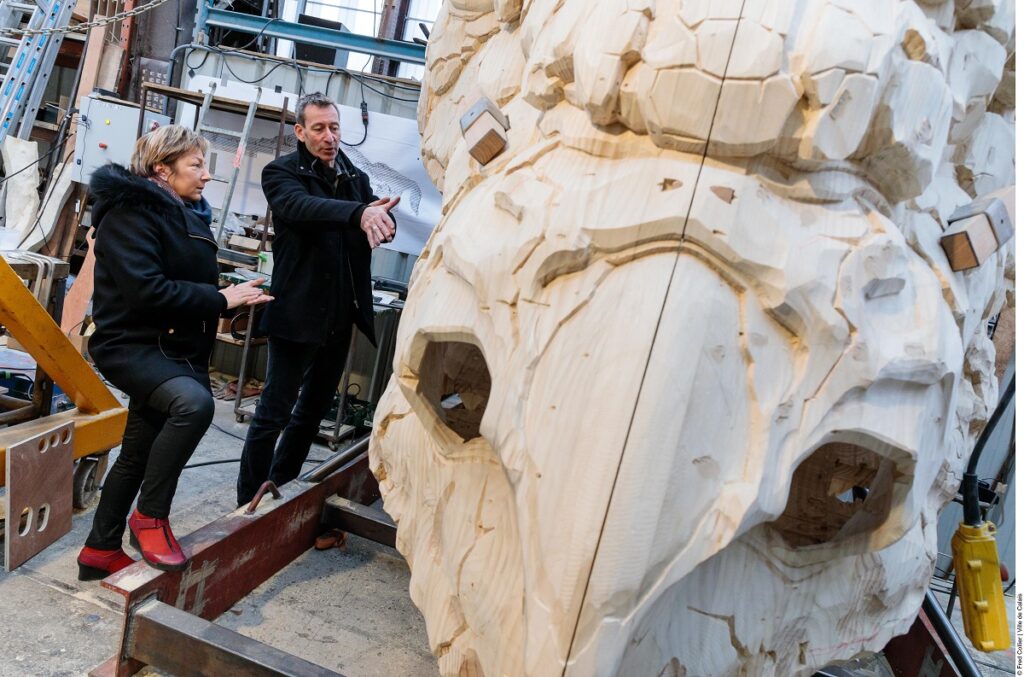 Natacha Bouchart alcaldesa de Calais y Francois Delaroziere, creador, mirando la cabeza de madera del dragón de Calais