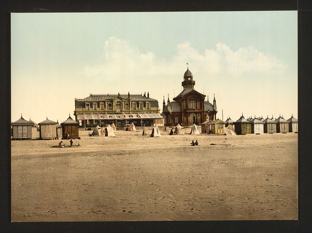 Una antigua postal coloreada a mano de la playa y el casino de Calais que muestra los dos edificios al final del tramo de arena